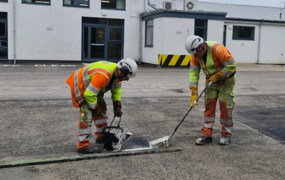 two workers laying out paint