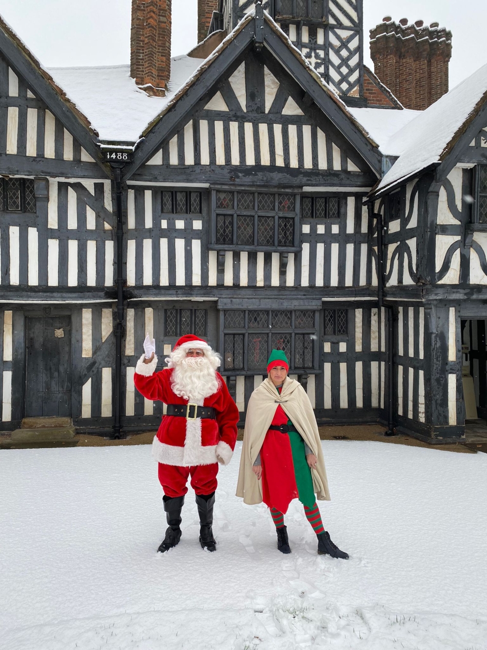 Santa and an elf in the snow outside Oak House Museu, West Bromwich