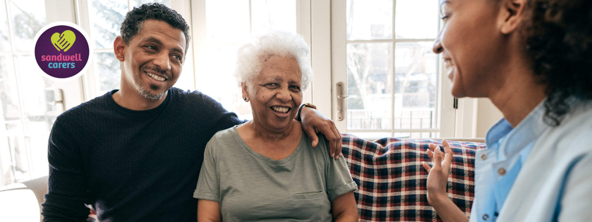 An older adult is supported by her family member and a health care professional
