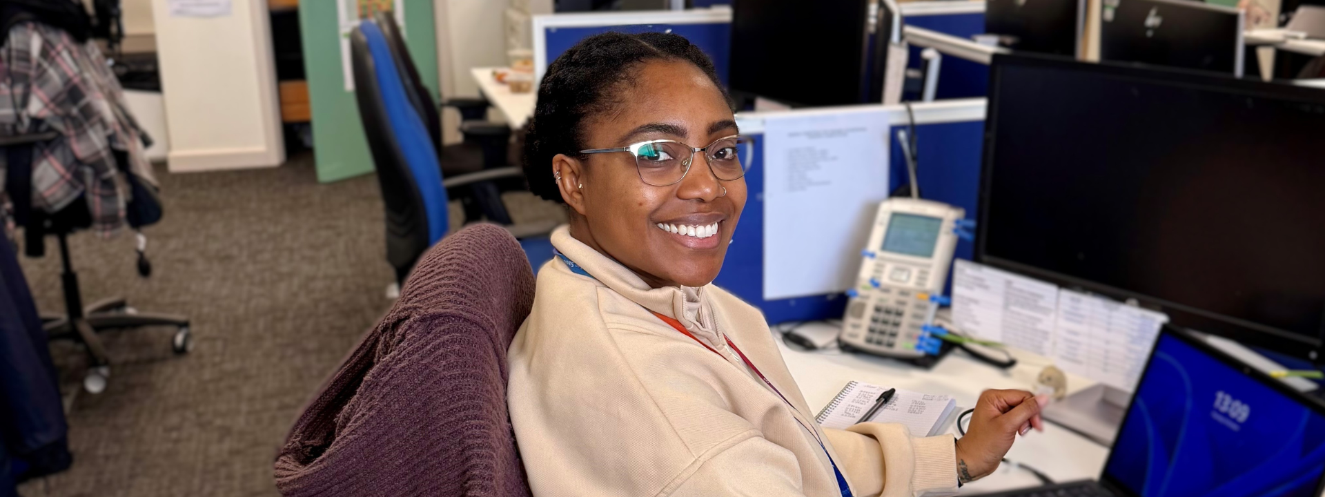 Friendly Adult Social Care colleague sat at her desk with laptop and phone
