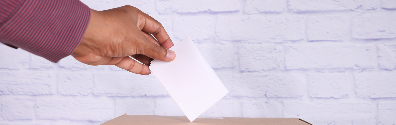 image of a man putting a ballot paper in a ballot box - elections