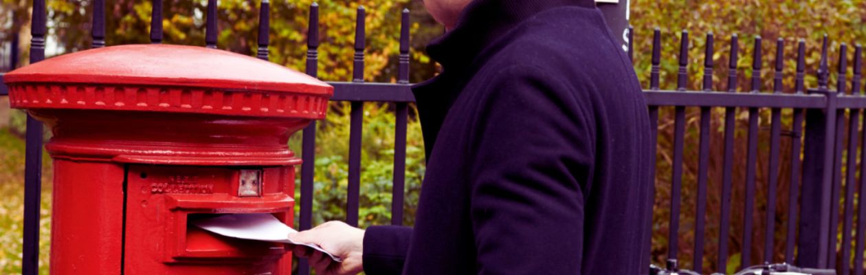 Image of a man putting a letter in a post box