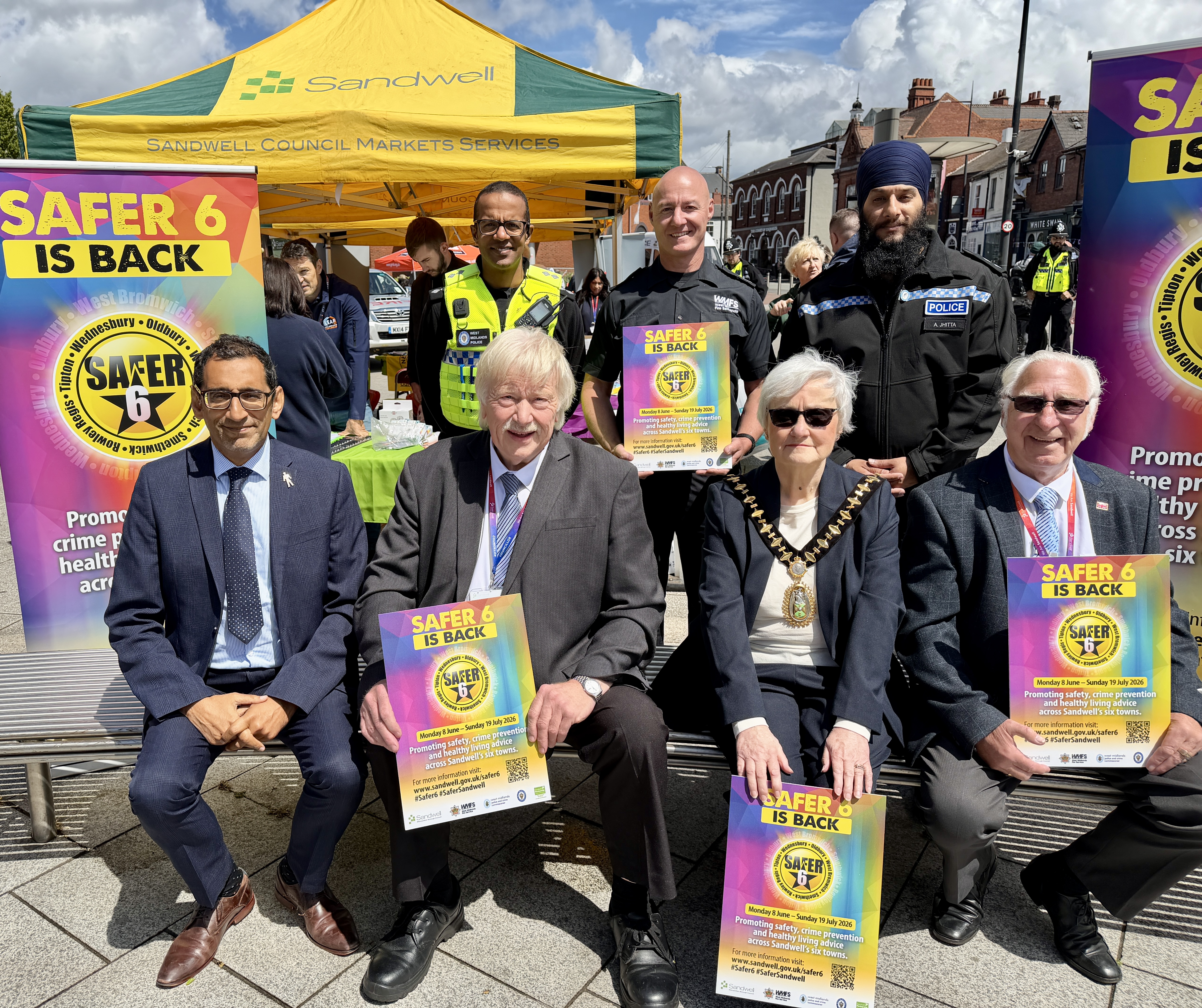 Group of senior officers from the council including the mayor and members of the Police and Fire Services pose for a picture in front of 2 Safer 6 Banners