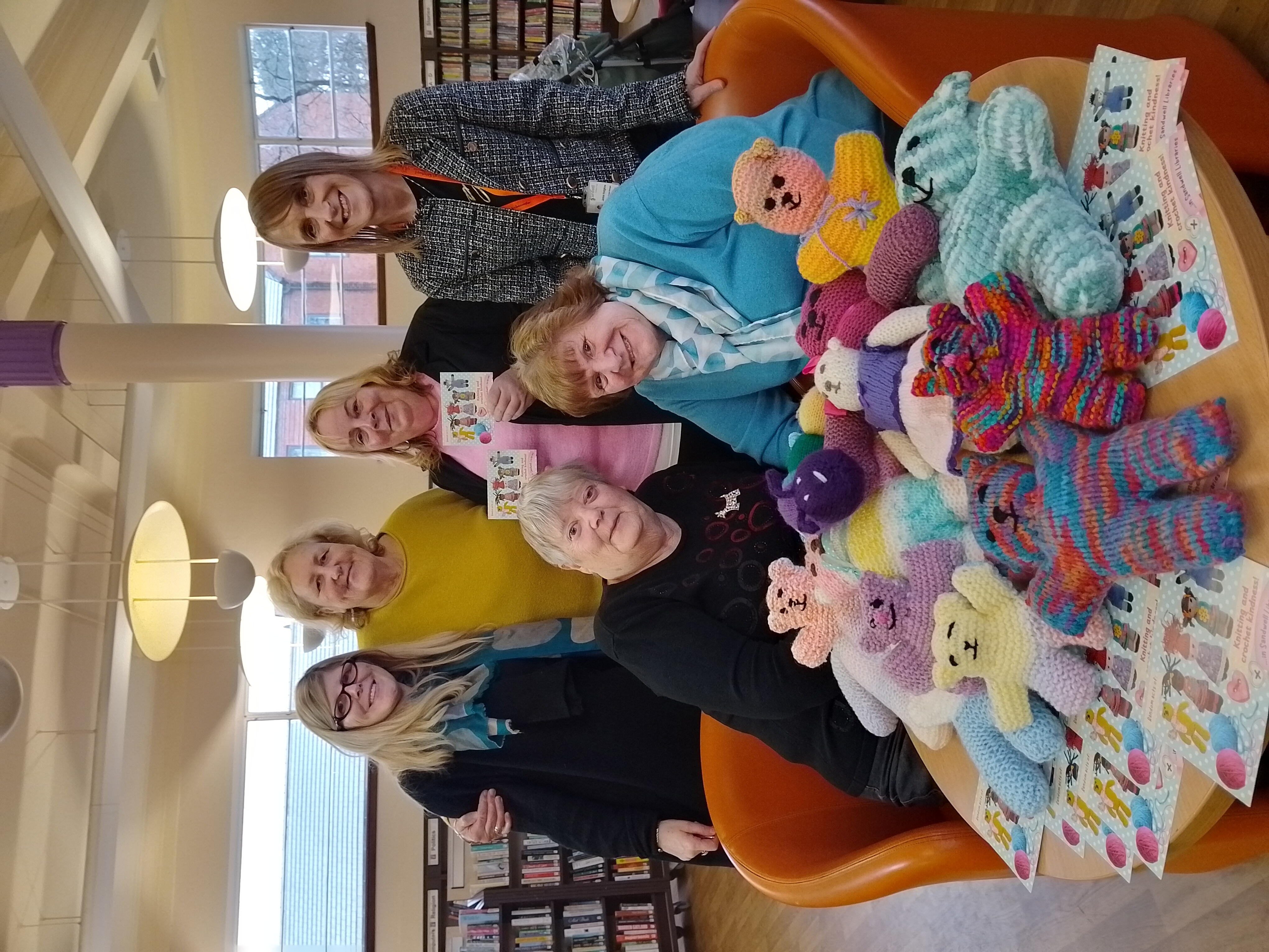 Image of 5 people with knitted soft toys in a library
