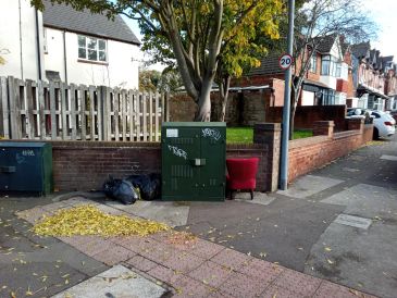 Red chair and bags of waste dumped at corner of road