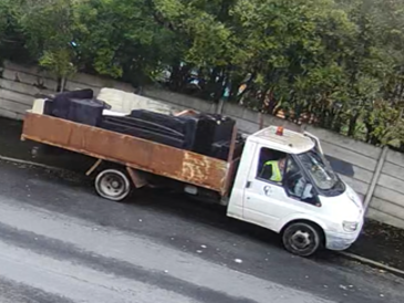 Low back van filled with waste driving down a road