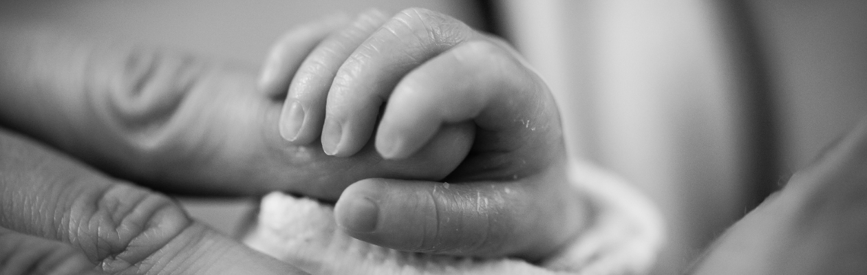 An image of a baby holding an adult's finger