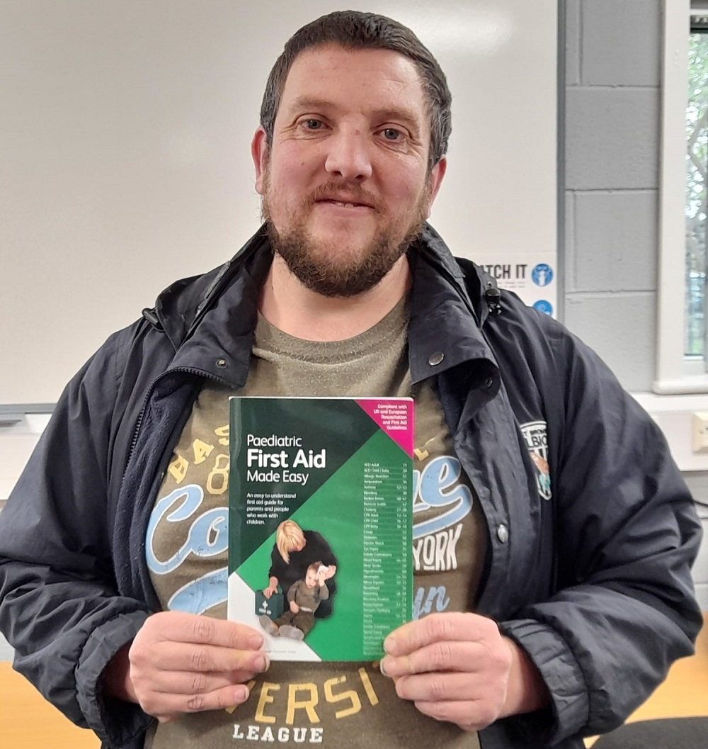 A photo of Michael holding a paediatric First Aid manual.